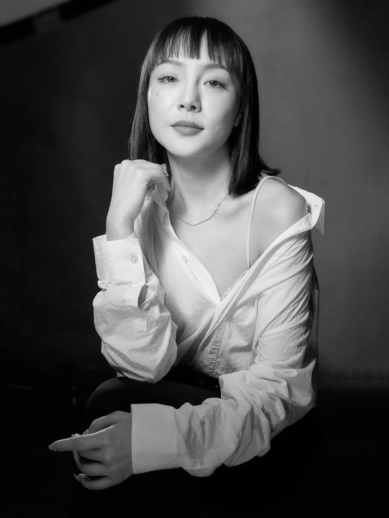 黑白肖像：一位女性以手轻触发梢，注视镜头