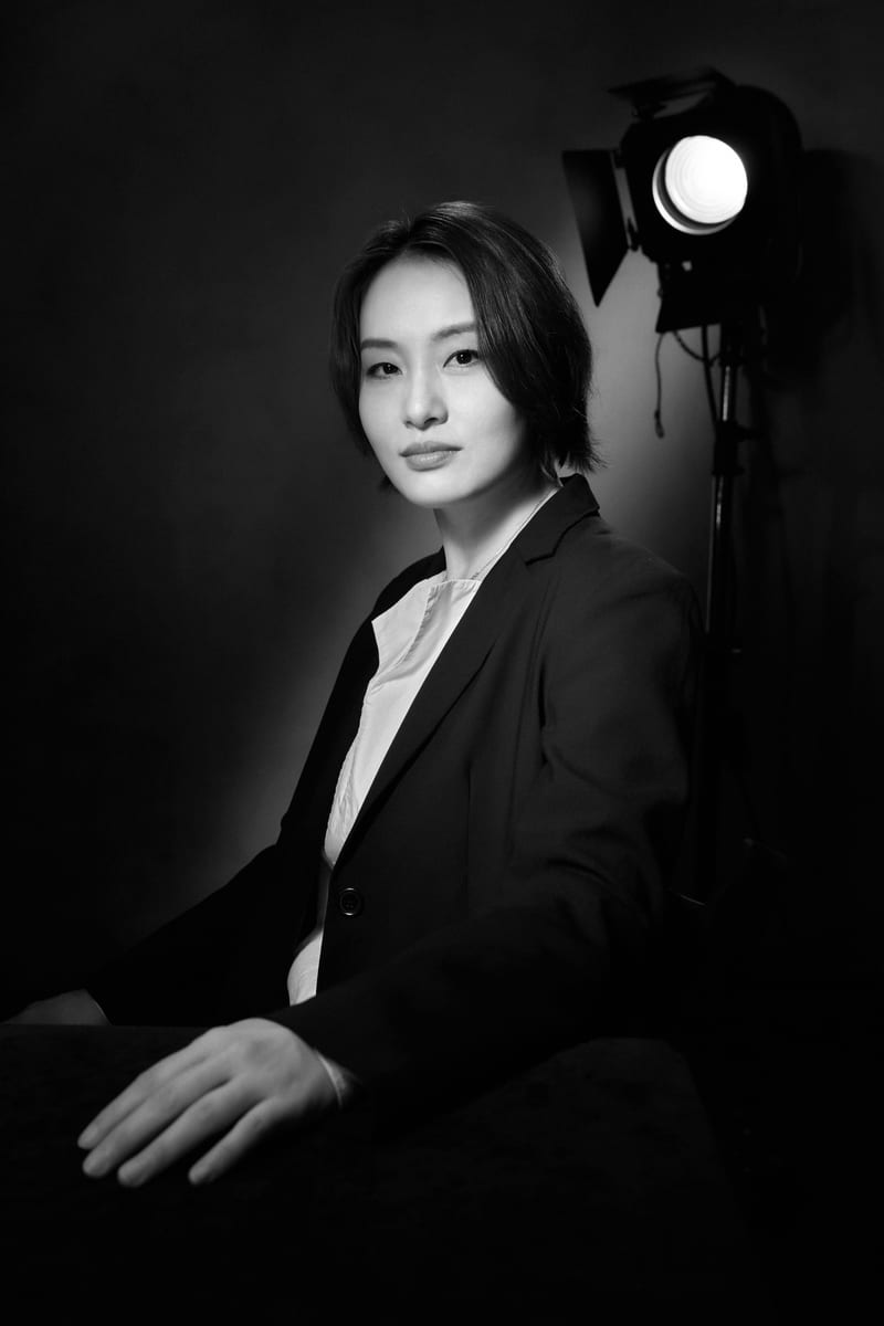 黑白肖像：穿西装的女性坐在摄影灯旁