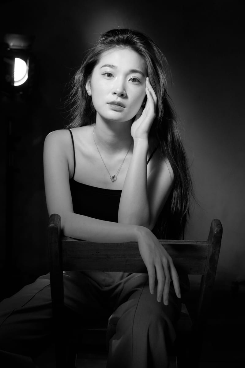 黑白肖像：女性坐在窗边，光从侧后方照来